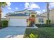 Two-story house with tan exterior, white garage door, and landscaping at 8458 Secret Key Cove, Kissimmee, FL 34747