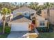 Two-story house with a tan exterior, white garage door, and landscaping at 8458 Secret Key Cove, Kissimmee, FL 34747