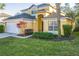 Two-story house, tan exterior, white garage door, landscaping, palm trees at 8458 Secret Key Cove, Kissimmee, FL 34747
