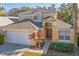 Two-story house with tan exterior, white garage door, and landscaping at 8458 Secret Key Cove, Kissimmee, FL 34747