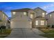 Two-story house with beige exterior, attached garage, and landscaping at 128 Higher Combe Dr, Davenport, FL 33897