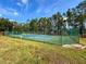 Outdoor tennis court with a green surface and chain-link fence at 128 Higher Combe Dr, Davenport, FL 33897