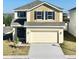 Two-story house with beige and yellow siding, dark blue accents and a two-car garage at 3019 Tackle Dr, Leesburg, FL 34748