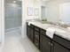 Spacious bathroom with granite countertops, dark wood cabinets, and a walk-in shower at 8956 Zurich Ln, Kissimmee, FL 34747