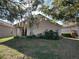 Rear view of a tan house with a covered patio, mature trees, and a well-maintained lawn at 5453 Shingle Creek Dr, Orlando, FL 32821
