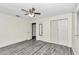 Bright bedroom with ceiling fan, grey wood-look floors, and double doors to closet at 5724 Se 2Nd St, Ocala, FL 34480