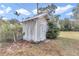 White storage shed with a gabled roof and wooden door at 5724 Se 2Nd St, Ocala, FL 34480