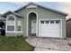 Light green house with white garage door and landscaping at 147 Dahlia Village Cir # Ge, Orlando, FL 32807