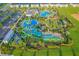 Aerial view of community pool with waterslides, palm trees, and expansive green space at 1636 Moon Valley Dr, Davenport, FL 33896