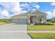 Single-story home with two-car garage, landscaped lawn, and inviting front porch at 6115 Claystone Way, Mount Dora, FL 32757