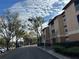 Tan building exterior with tree-lined road and parking at 7511 Seurat St # 10301, Orlando, FL 32819