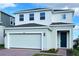 Two-story house with white and light-green siding, two-car garage, and landscaping at 6858 Spanish Imperial St, Howey In The Hills, FL 34737
