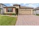 Tan one-story house with red shutters, two-car garage, and landscaped yard at 1380 Clear Brook Pl, St Cloud, FL 34772