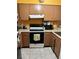 Bright kitchen features brown cabinets, white appliances, and tile flooring at 262 Scottsdale Sq # 262, Winter Park, FL 32792