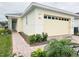 Two-car garage, light-colored exterior, and landscaped walkway at 7520 Castlewood Ct, Harmony, FL 34773