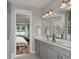 Double vanity bathroom with gray cabinets and a large mirror at 1104 Western Blue Way, Minneola, FL 34715