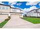Townhome exterior showcasing two-car garage and landscaping at 664 Benoi Dr, Davenport, FL 33896