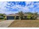 Single-story home with stone facade, dark gray garage door, and mature landscaping at 6928 Sugarbush Dr, Orlando, FL 32819