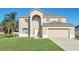 Two-story house with beige exterior, two-car garage, and manicured lawn at 415 Big Sioux Ct, Kissimmee, FL 34759