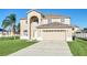 Two-story house with beige exterior, two-car garage, and manicured lawn at 415 Big Sioux Ct, Kissimmee, FL 34759