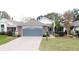 Single-story home with gray garage door, landscaping, and paved driveway at 25001 Cranes Roost Cir, Leesburg, FL 34748