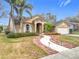 Tan house with a two-car garage and landscaped yard at 823 Elm Forest Dr, Minneola, FL 34715