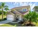 Two-story house with attached garage, landscaped yard, and palm trees at 20106 Sunset Landing Ave, Groveland, FL 34736