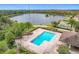 Community pool with lake view, surrounded by lush landscaping and tennis courts at 10951 Savannah Landing Cir, Orlando, FL 32832