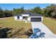 Single-story home with white exterior, black garage door, and a grassy yard at 6215 148Th Southwest, Ocala, FL 34473
