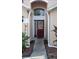 Inviting entryway with a burgundy door and landscaping at 7947 Golden Pond Cir, Kissimmee, FL 34747