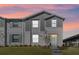 Two-story townhome with gray siding, light-colored trim, and a small front yard at dusk at 276 Jetty Way, Davenport, FL 33897