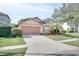 Tan one-story house with brown garage door, landscaping, and driveway at 12755 Oulton Cir, Orlando, FL 32832
