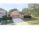 Tan one-story house with brown garage door, landscaping, and driveway at 12755 Oulton Cir, Orlando, FL 32832
