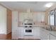 Kitchen with white cabinets, stove, and a double sink at 1618 Cypress Pt, Lady Lake, FL 32159