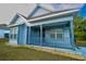 Newly built home featuring light blue exterior, covered porch, and well-manicured lawn at 535 W Silver Springs Pl, Ocala, FL 34475