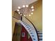 Impressive curved staircase with a chandelier and dark wood accents at 6895 Se 96Th Place Rd, Belleview, FL 34420
