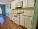 White kitchen cabinets and appliances with laminate flooring at 10787 Sw 53Rd Cir, Ocala, FL 34476