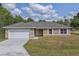 Charming one-story home with a white garage door and landscaped lawn at 13899 Sw 89Th St, Dunnellon, FL 34432