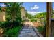 Landscaped backyard with a brick pathway, lush greenery, and a wooden pergola at 567 Silver Course Run, Ocala, FL 34472