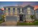 Two-story home with gray siding, stone accents, and a two-car garage at 3004 Mahalo Dr, Davenport, FL 33897
