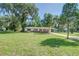 House with a large front yard, driveway, and mature trees at 2429 Cr 451, Lake Panasoffkee, FL 33538