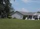 Single story home with grey siding, green lawn, and mature trees at 612 Fannich Ct, Leesburg, FL 34788