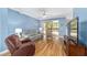 Spacious living room with hardwood floors, a large TV, and access to backyard at 8678 Sw 83Rd Cir, Ocala, FL 34481