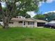 Tan single-story house with a large tree and a black SUV in the driveway at 10765 Sw 62Nd Ter, Ocala, FL 34476