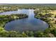 Aerial view of a serene lake surrounded by lush greenery and homes at 15669 Se 112Th Ln, Ocklawaha, FL 32179