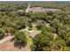 Aerial view of a house nestled in a wooded area with a paved road nearby at 10020 Sw 202Nd Cir, Dunnellon, FL 34431