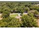 Aerial view showcasing a house surrounded by lush greenery and a quiet residential road at 10020 Sw 202Nd Cir, Dunnellon, FL 34431