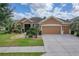 Tan two-story house with three car garage and landscaping at 9818 Sw 63Rd Loop, Ocala, FL 34481