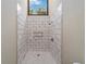 Large walk-in shower with marble-style tile and a built-in shelf at 14260 Ne 40Th Ct, Anthony, FL 32617