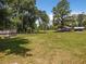 Large grassy yard with trees and a home in the background at 5401 Se 162Nd St # 32, Summerfield, FL 34491